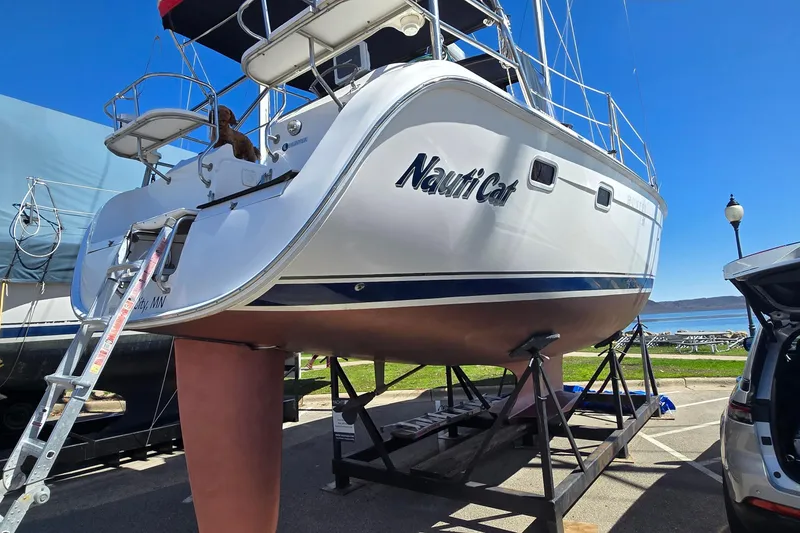 Slide: The Image of Hunter 38 sailboat from 2005, named "Nauti Cat," on a stand near the water. - 33