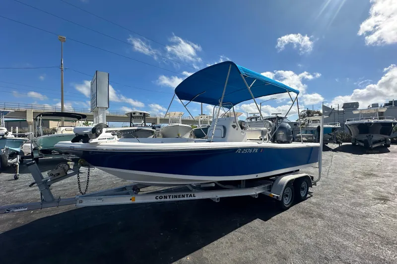 The Image of 2015 Tidewater 2000 Carolina Bay boat with blue canopy on trailer, sunny day. - 0