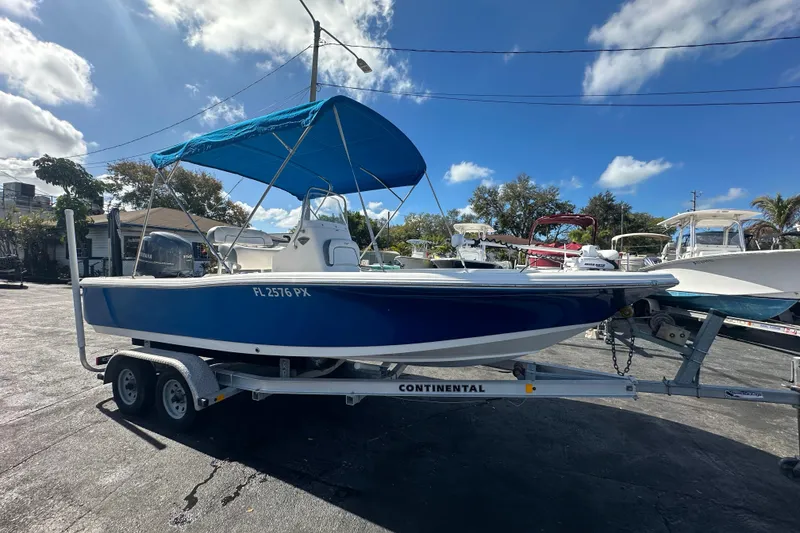 Slide: The Image of 2015 Tidewater 2000 Carolina Bay boat on trailer with blue canopy, parked outdoors. - 7