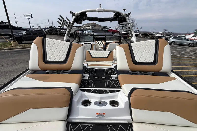 Slide: The Image of 2021 Tigé 25ZX boat interior with tan and white seating, docked in a marina. - 14