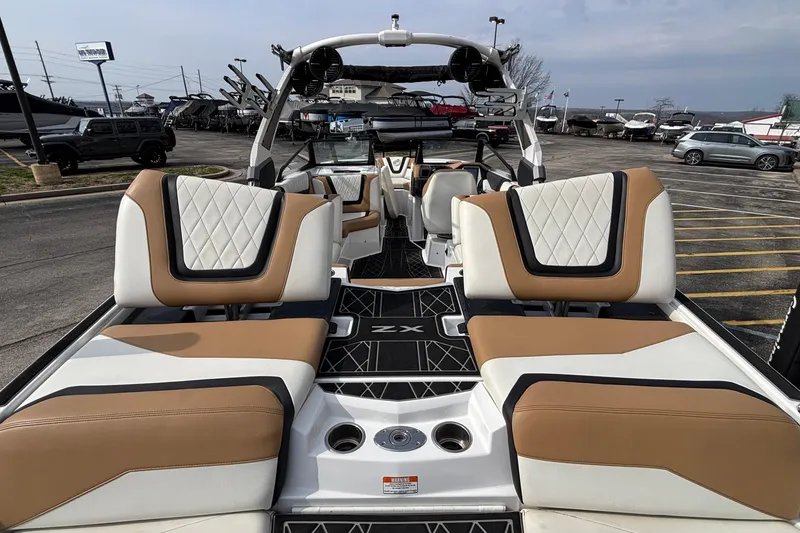 Slide: The Image of 2021 Tigé 25ZX boat interior with luxurious tan and white seating in a parking lot. - 16