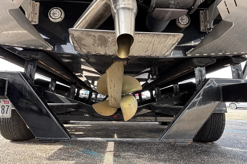 Slide: The Image of Underneath view of 2021 Tigé 25ZX boat on trailer, showcasing propeller and exhaust. - 20