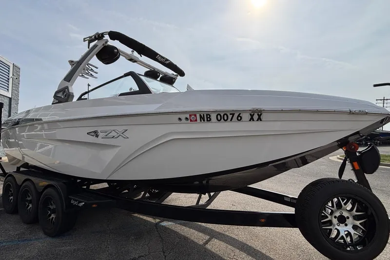 Slide: The Image of 2021 Tigé 25ZX boat on trailer, sleek design, parked outdoors. - 3