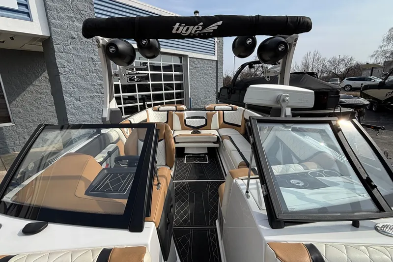 Slide: The Image of 2021 Tigé 25ZX boat interior with tan and white seating, black accents, and tower speakers. - 37