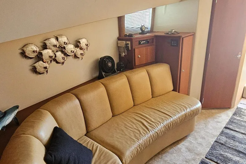Slide: The Image of 2005 Silverton 330 Sport Bridge interior with beige sofa, fish wall art, and wooden cabinetry. - 10