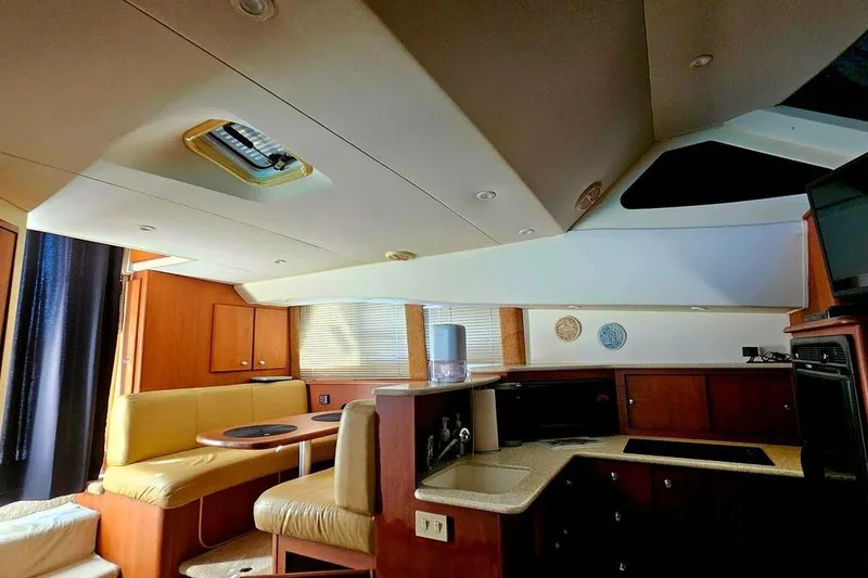 Slide: The Image of 2005 Silverton 330 Sport Bridge interior with kitchen and dining area, featuring wood cabinetry. - 11