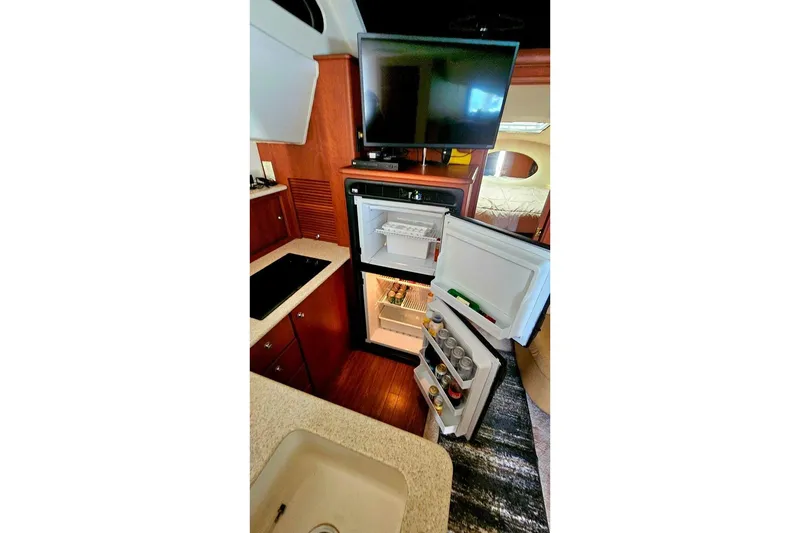 Slide: The Image of 2005 Silverton 330 Sport Bridge interior with open fridge and TV in kitchen area. - 16