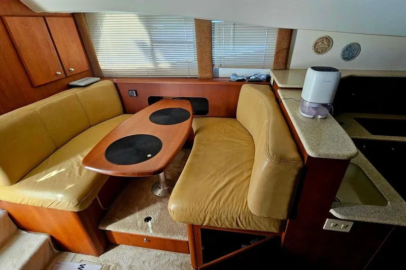 Slide: The Image of Interior of 2005 Silverton 330 Sport Bridge with cozy seating and wooden table. - 6