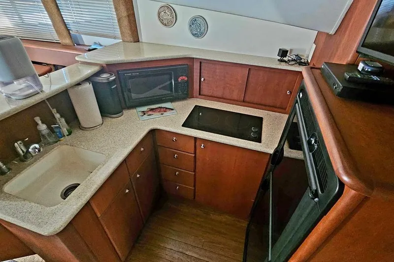 Slide: The Image of 2005 Silverton 330 Sport Bridge yacht kitchen with modern appliances and wooden cabinetry. - 8