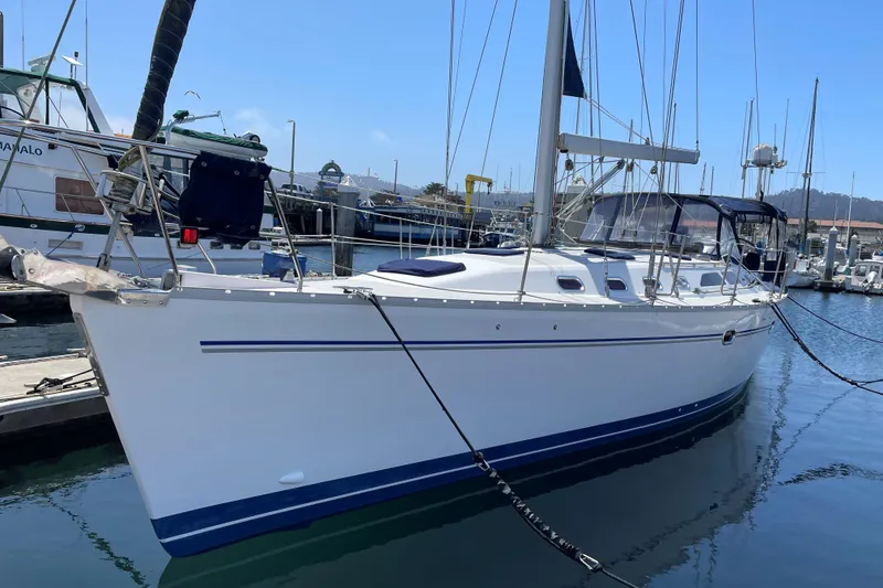 Slide: The Image of 2005 Catalina 470 sailboat docked at marina, featuring sleek white hull and blue accents. - 1