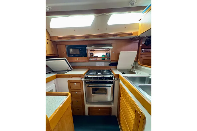 Slide: The Image of 2005 Catalina 470 yacht kitchen with stove, microwave, and wooden cabinetry. - 16