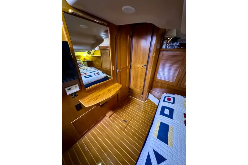 Slide: The Image of Interior of 2005 Catalina 470 yacht with wooden finishes and nautical-themed bedding. - 22