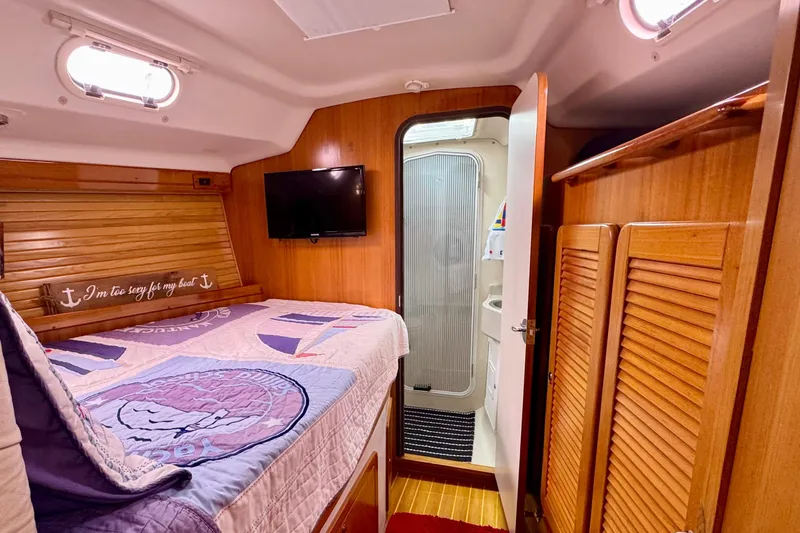 Slide: The Image of Cozy cabin interior of 2005 Catalina 470 sailboat with bed, TV, and bathroom. - 24