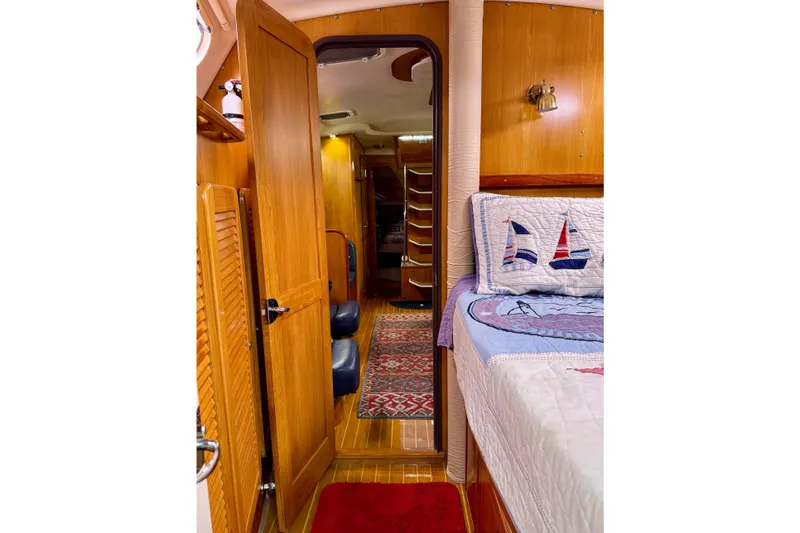 Slide: The Image of Interior of 2005 Catalina 470 yacht, featuring cozy cabin with nautical-themed bedding. - 25