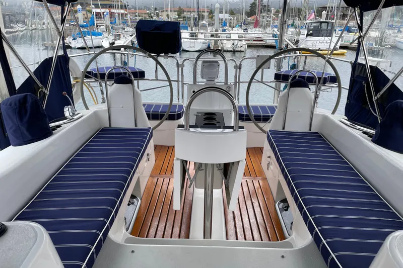 Slide: The Image of 2005 Catalina 470 yacht cockpit with striped seating and dual steering wheels in marina. - 8