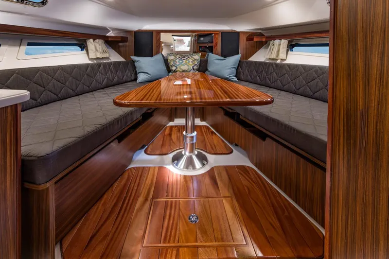 Slide: The Image of Manufacturer Provided Image: 2016 Pursuit OS 355 Offshore cabin with wooden table and cushioned seating. - 5