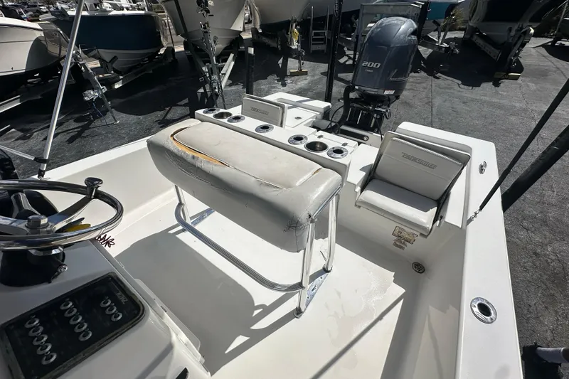 Slide: The Image of 2012 Pathfinder 2200 V boat interior with seating and steering wheel, docked outdoors. - 15
