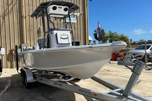 The Image of 2026 Sea Pro 210 Bay boat on trailer, parked outdoors near a building. - 1