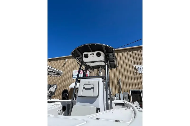 Slide: The Image of 2026 Sea Pro 210 Bay boat with T-top, parked outdoors under clear blue sky. - 4