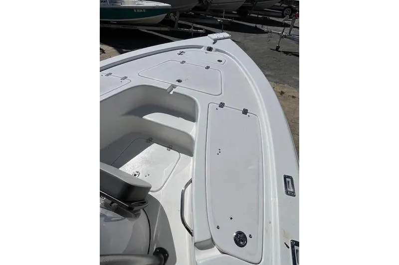 Slide: The Image of 2026 Sea Pro 210 Bay boat deck with storage compartments, in a marina setting. - 8