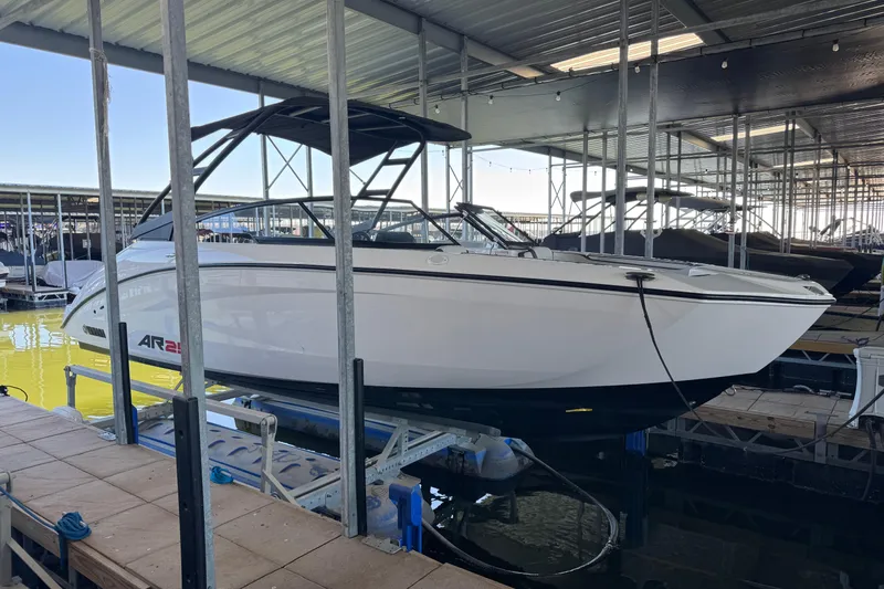 The Image of 2024 Yamaha Boats AR250 in marina, white hull, black canopy, docked on lift. - 1