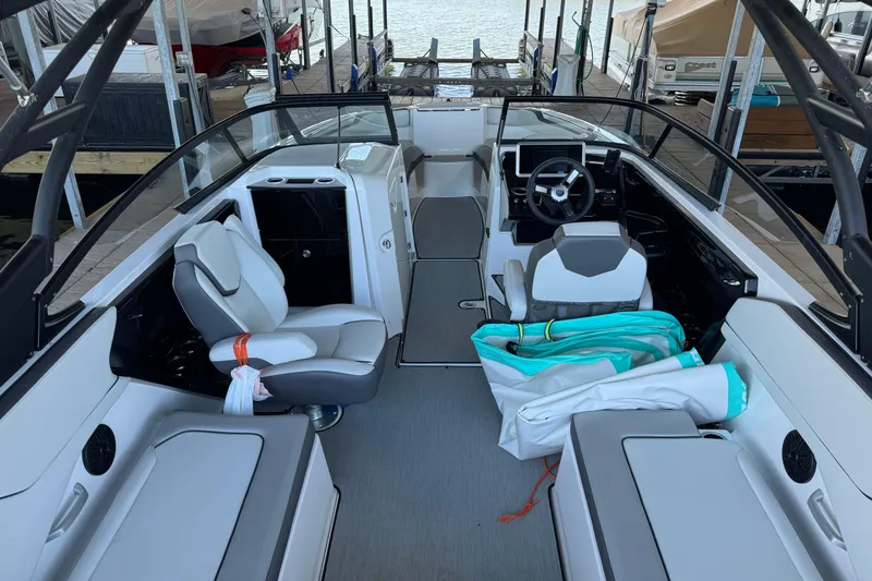 Slide: The Image of 2024 Yamaha Boats AR250 interior with modern seating and steering wheel, docked at marina. - 7
