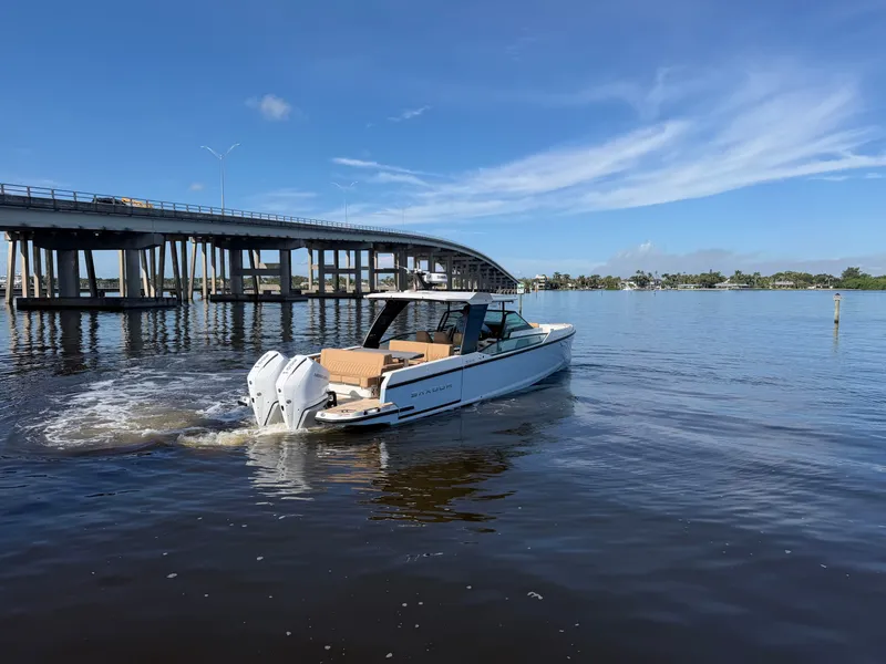 Slide: The Image of A 2027 Saxdor 320 GTO cruising on calm waters under a bridge. - 3