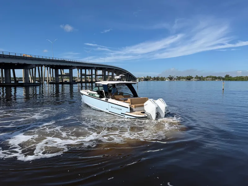 Slide: The Image of 2027 Saxdor 320 GTO on calm water under a bridge, featuring twin outboard engines. - 5