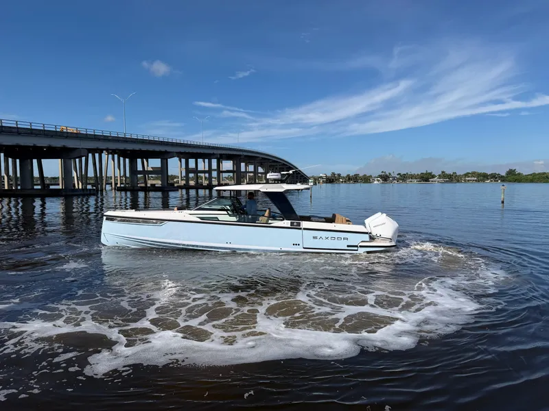 Slide: The Image of A 2027 Saxdor 320 GTO cruising on calm water beneath a bridge. - 6