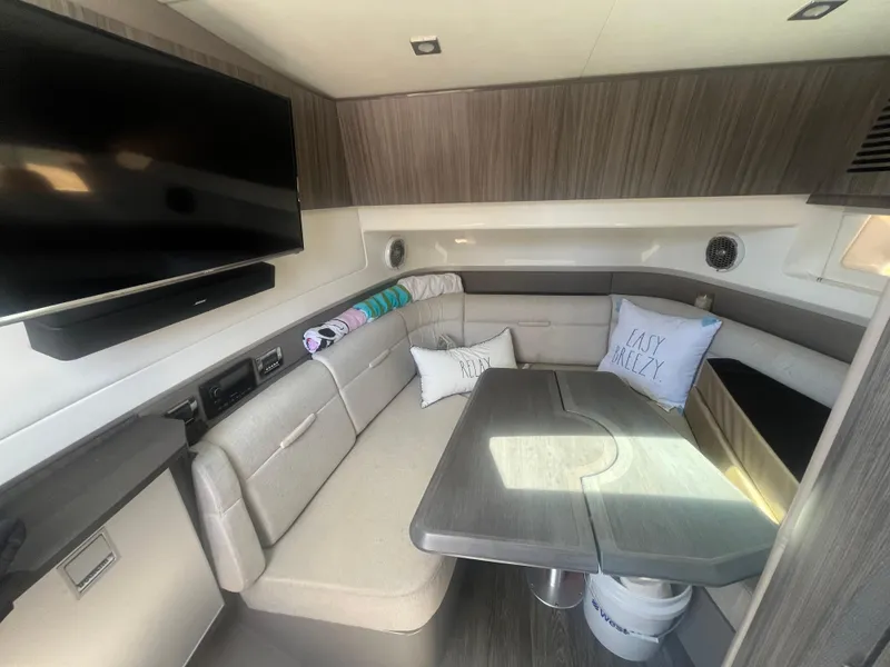 Slide: The Image of 2018 Sea Ray SLX 400 interior with seating, table, and mounted TV. - 9