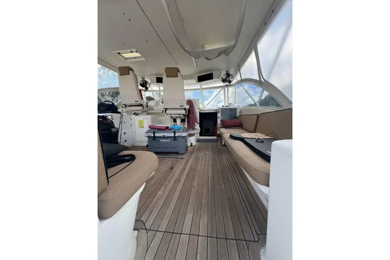 Slide: The Image of 1999 Ocean Yachts 48 Express interior with seating and helm, featuring wooden flooring. - 3