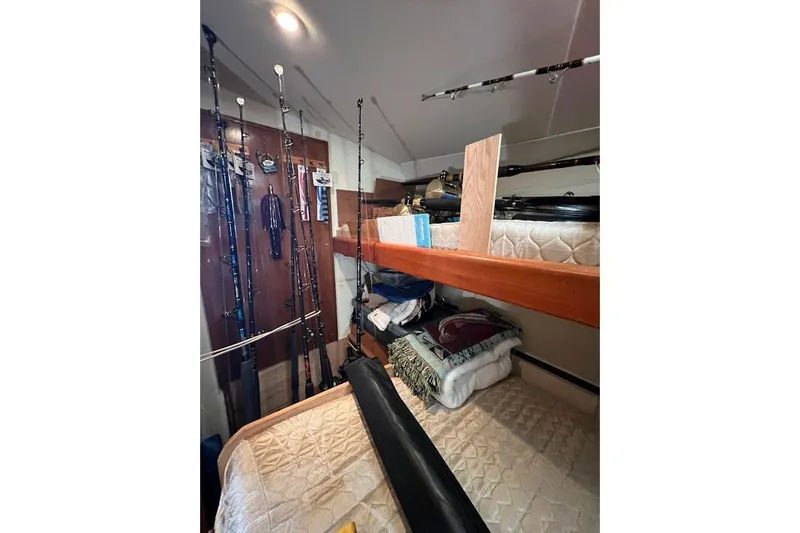 Slide: The Image of 1999 Ocean Yachts 48 Express cabin with fishing rods and bunk beds. - 36