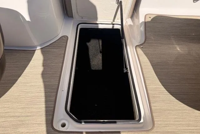 Slide: The Image of 2013 Regal 2500 Bowrider storage compartment with open hatch on beige carpeted floor. - 27