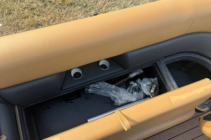 Slide: The Image of 2026 Bentley Pontoons Elite 253 Swingback storage compartment with tan seating and accessories. - 12