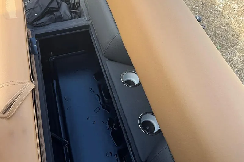 Slide: The Image of 2026 Bentley Pontoons Elite 253 Swingback storage compartment with tan seating and cup holders. - 16