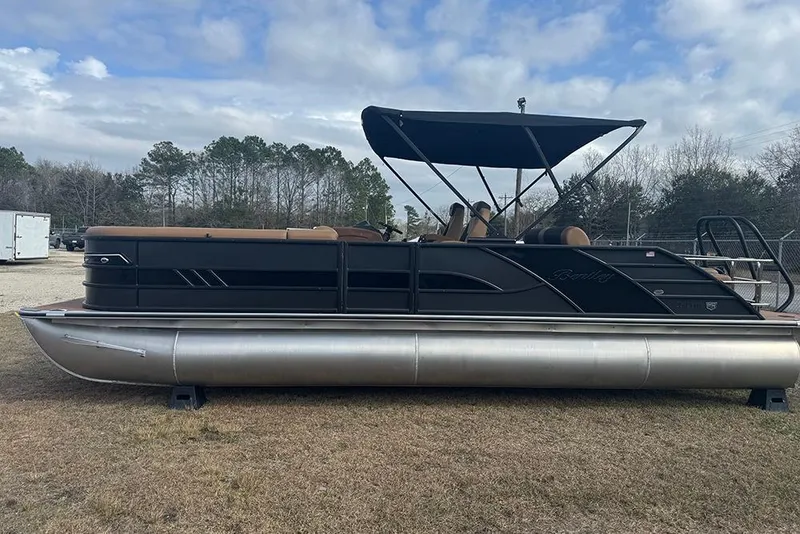 Slide: The Image of 2026 Bentley Pontoons Elite 253 Swingback Dual Captain Full Tritoon on grass, under cloudy sky. - 2