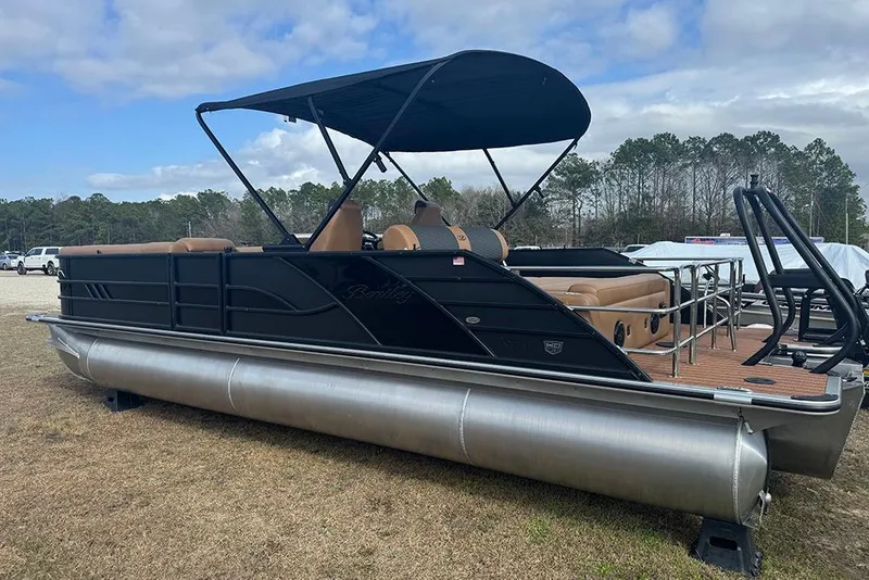 Slide: The Image of 2026 Bentley Pontoons Elite 253 Swingback Dual Captain Full Tritoon on grassy area, under cloudy sky. - 3