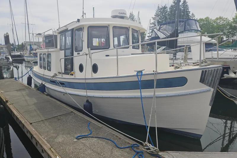 Slide: The Image of 1998 Nordic Tug 32 docked at a marina, showcasing classic design and sturdy build. - 1