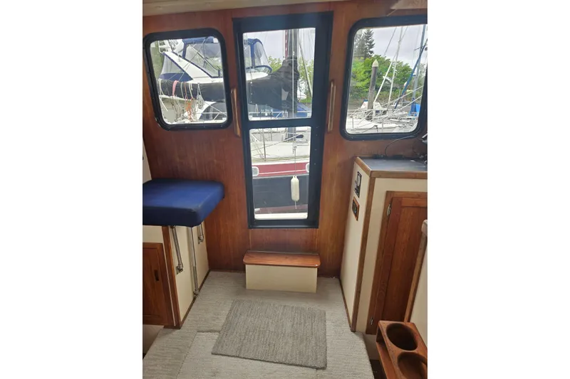 Slide: The Image of Interior view of a 1998 Nordic Tug 32, showcasing wooden cabinetry and marina view. - 12