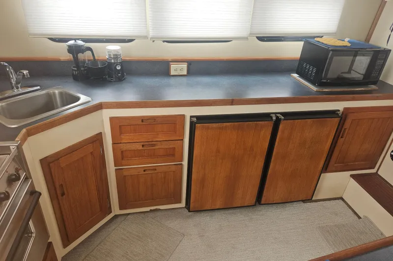 Slide: The Image of 1998 Nordic Tug 32 galley with wooden cabinets, sink, microwave, and coffee maker. - 16