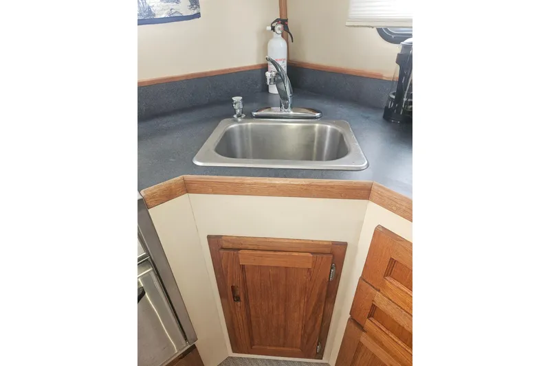 Slide: The Image of 1998 Nordic Tug 32 galley with sink, wooden cabinets, and countertop. - 17