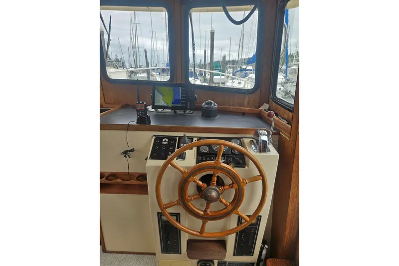 Slide: The Image of Nordic Tug 32 helm with wooden wheel, navigation equipment, and marina view, 1998 model. - 22