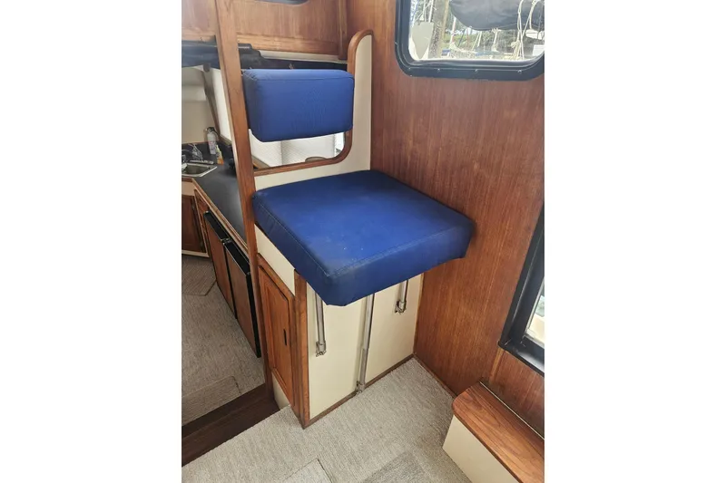Slide: The Image of 1998 Nordic Tug 32 interior with blue cushioned seating and wooden cabinetry. - 27