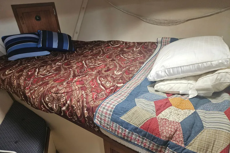 Slide: The Image of Cozy cabin bed in a 1998 Nordic Tug 32, with patterned quilts and pillows. - 36