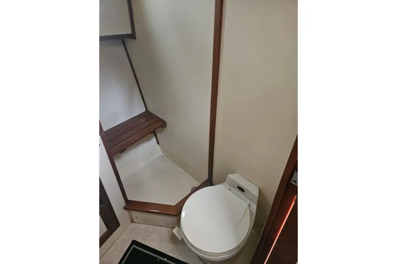 Slide: The Image of Bathroom interior of a 1998 Nordic Tug 32, featuring a toilet and wooden bench. - 40