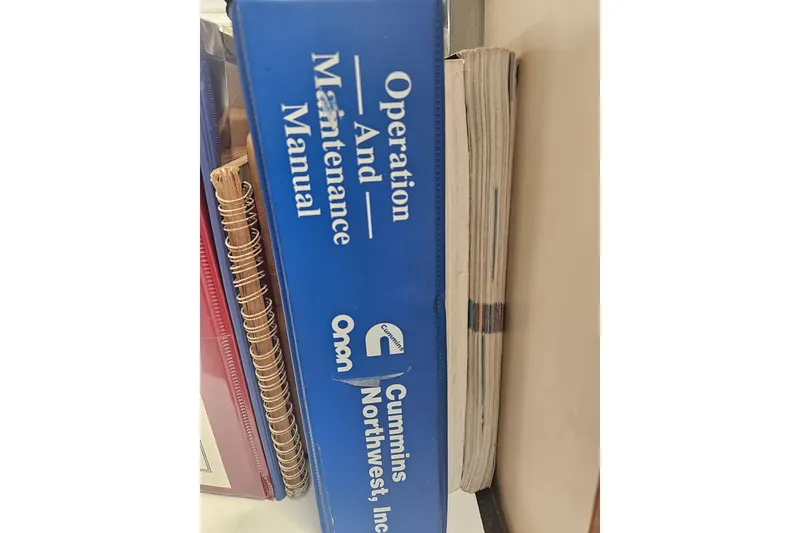 Slide: The Image of Blue operation and maintenance manual for Cummins Northwest, Inc., next to spiral-bound notebooks. Nordic Tug 32, 1998. - 59