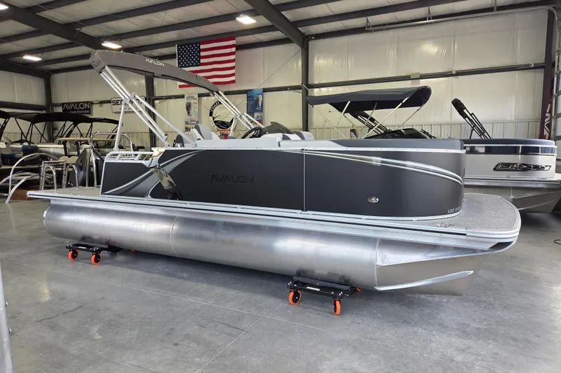 The Image of 2026 Avalon LSZ 2185 Cruise Rear Bench pontoon boat in showroom with American flag. - 0