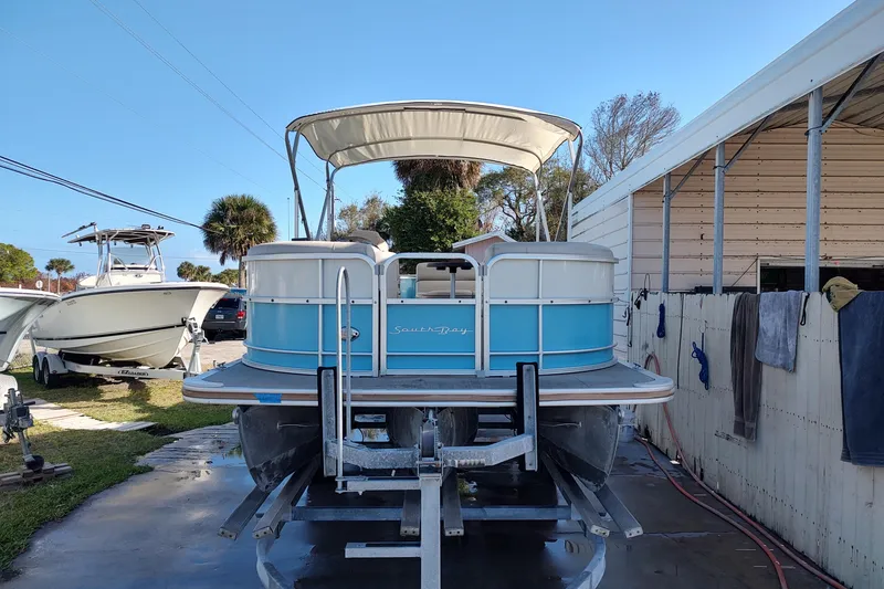 Slide: The Image of 2019 South Bay S222FCR pontoon boat on trailer, blue and white design, outdoor setting. - 4