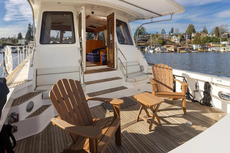 Slide: The Image of Grand Banks 54 Eastbay SX 2003 yacht with wooden deck and chairs by the water. - 15