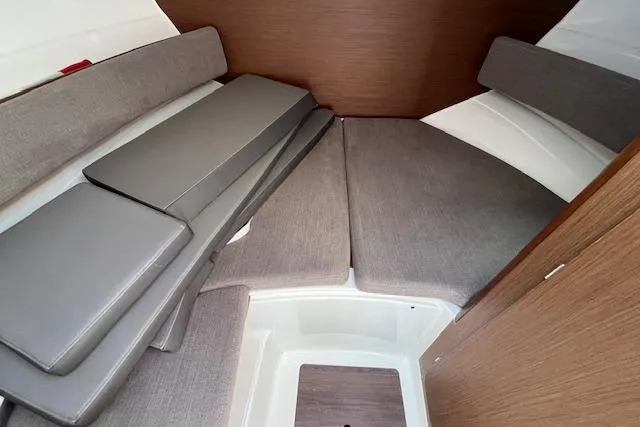 Slide: The Image of 2023 Beneteau Antares 8 cabin interior with gray cushions and wood accents. - 10